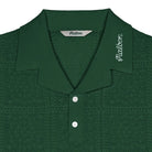 Green knitted polo shirt with brand label on a white background