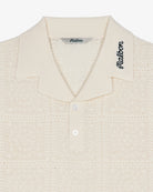Close-up of a textured beige shirt with 'Malbon' branding on a white background