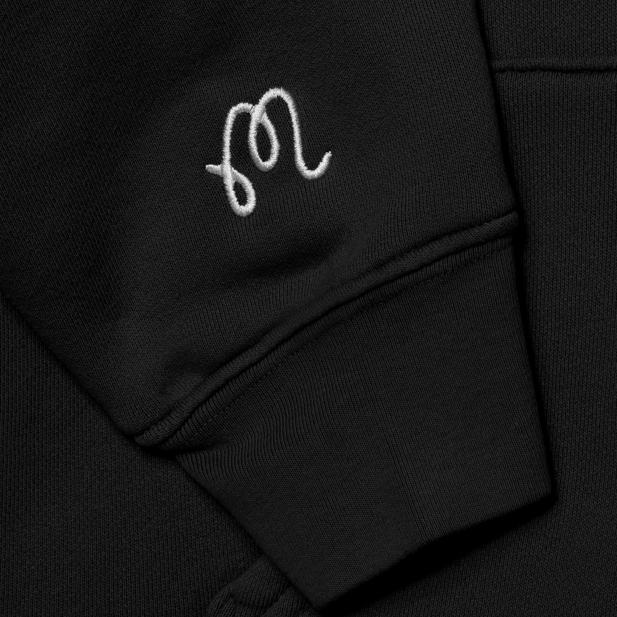 Close up of an embroidered M on a black sleeve