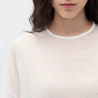 Person wearing a sheer white colored oversized t-shirt against a white background