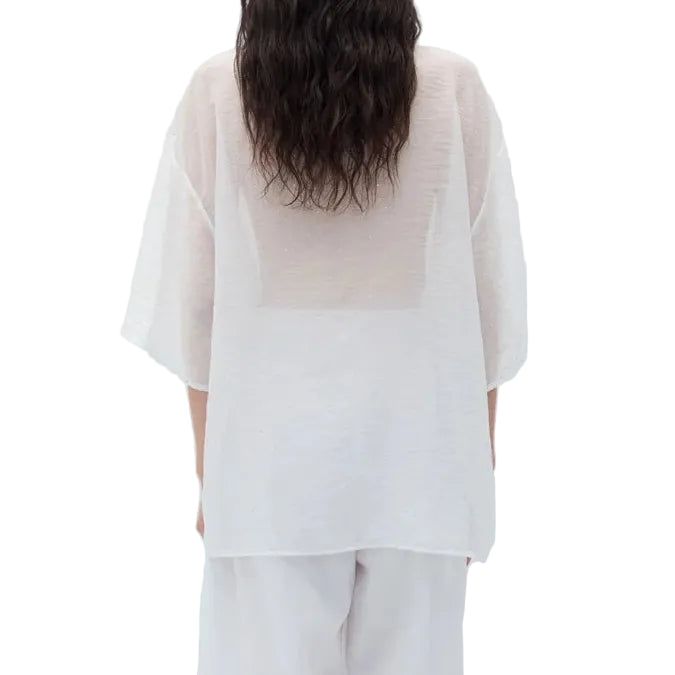 Back view of a person wearing an oversized sheer white t-shirt with wide-leg pants on a white background