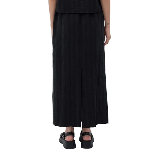 Person wearing a black outfit with a long skirt and top on a white background