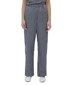 A model wearing a black and white gingham checkered outfit with wide-leg trousers, paired with white shoes, against a plain white background.