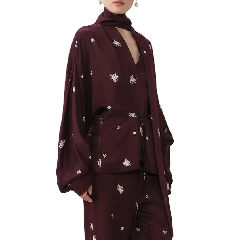 Woman wearing a burgundy outfit with floral patterns on a white background