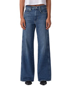Person wearing a white t-shirt and blue jeans on a plain background