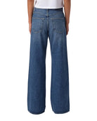 Person wearing blue wide-leg jeans and a white t-shirt on a plain background
