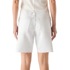 Person wearing a white sleeveless top and white shorts on a plain background