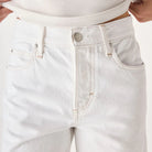White jeans worn by a person on a plain background