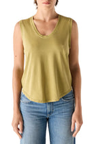Person in a green sleeveless tank and blue jeans on a white background