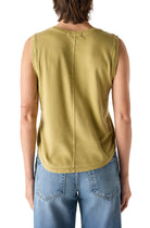 Person in a green sleeveless tank and blue jeans on a white background