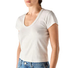 Person wearing a plain white t-shirt and blue jeans on a light gray background
