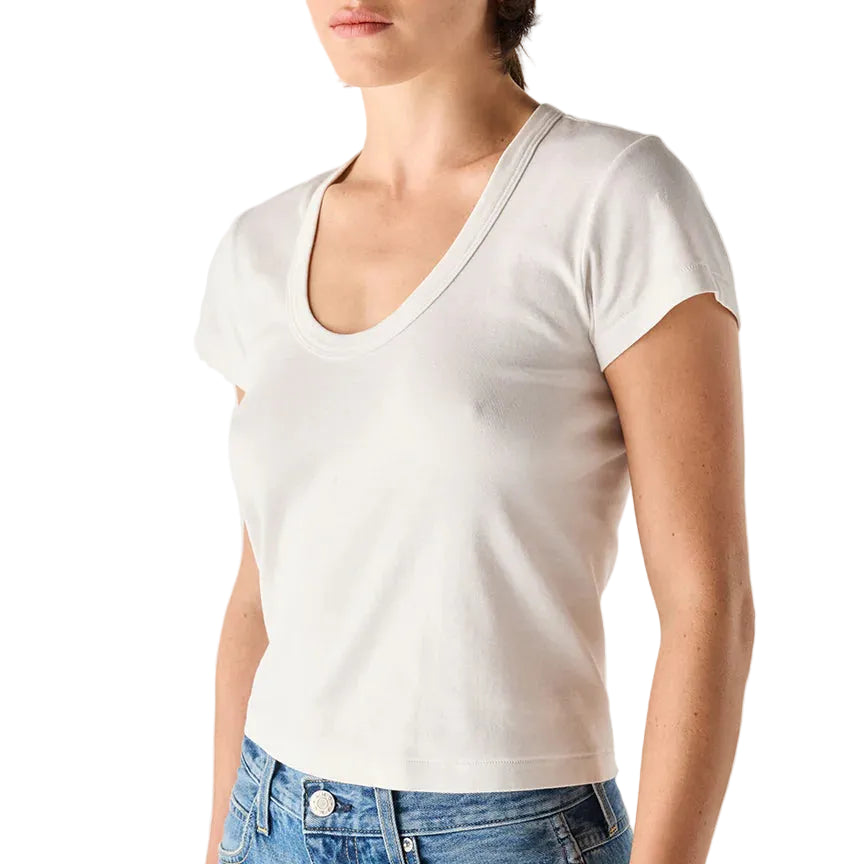 Person wearing a plain white t-shirt and blue jeans on a light gray background