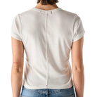 Person wearing a white top and blue jeans on a plain background