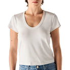 Person wearing a plain white t-shirt and blue jeans on a light background