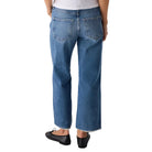 Person wearing a white top and blue jeans on a plain background