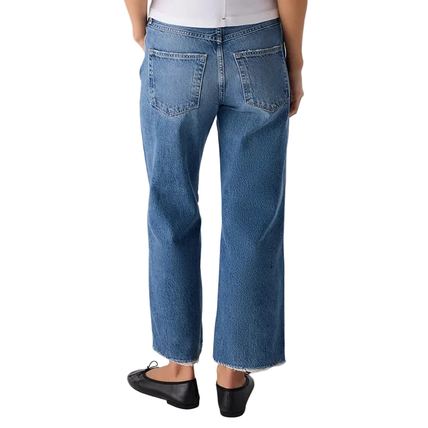 Person wearing a white top and blue jeans on a plain background