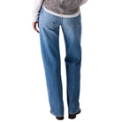 Person wearing a gray t-shirt over a white shirt and blue jeans on a white background