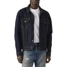 Man wearing a dark denim jacket and light blue jeans on a white background