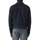 Person wearing a dark denim jacket and blue jeans on a white background