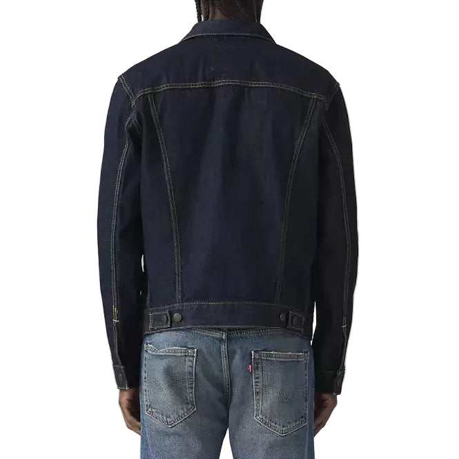Person wearing a dark denim jacket and blue jeans on a white background