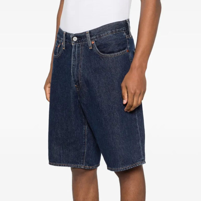 Person wearing dark blue denim shorts on a white background