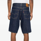 Person wearing dark blue denim shorts on a white background
