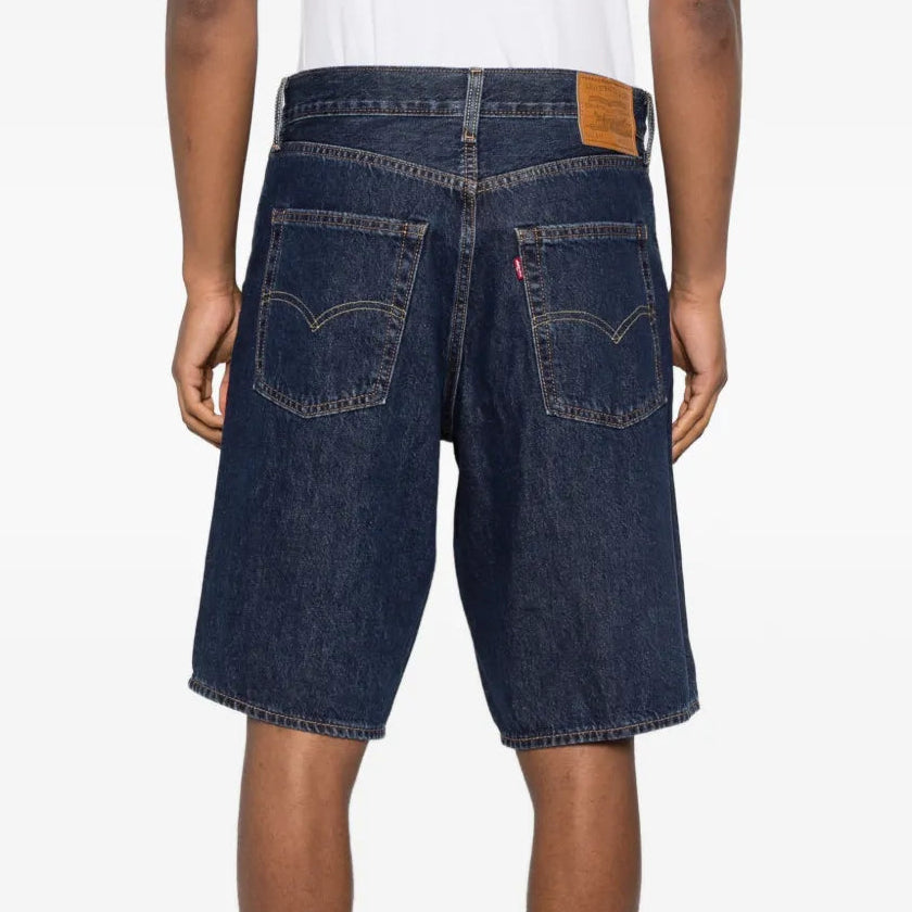 Person wearing dark blue denim shorts on a white background