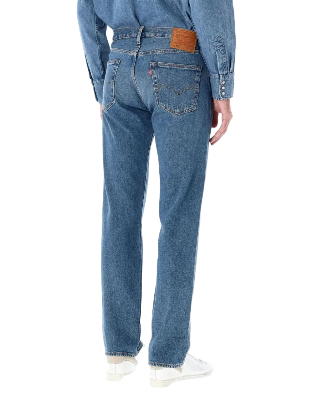 Person wearing blue jeans and a denim jacket on a white background