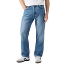 Man wearing a white t-shirt and blue jeans on a plain background