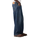 Person wearing a white t-shirt and blue jeans on a plain background
