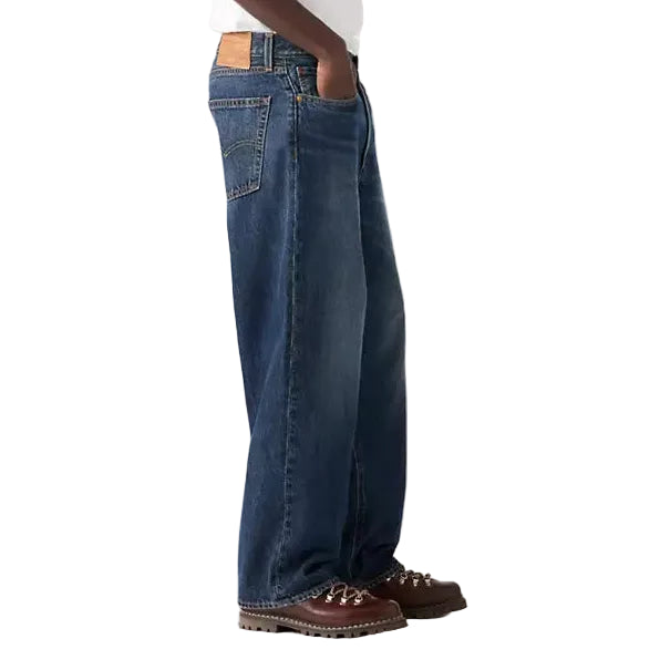 Person wearing a white t-shirt and blue jeans on a plain background