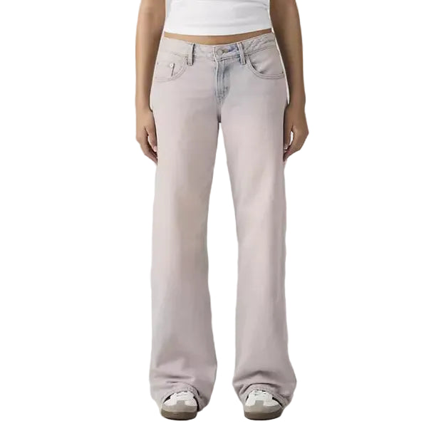Person wearing a white tank top and light pink jeans on a plain background