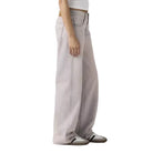Person wearing a white tank top and light gray pants on a plain background