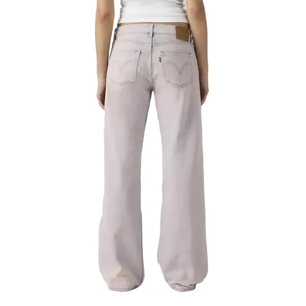 Woman wearing a white sleeveless top and light pink pants on a plain background