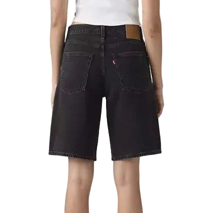 Black denim shorts worn by a person on a plain background