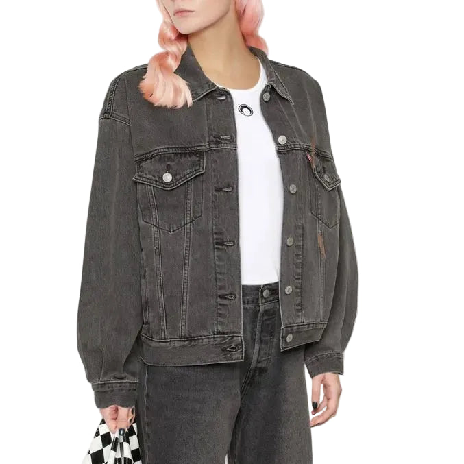 Person wearing a black denim jacket, white shirt, gray jeans, and red and white sneakers, holding a black and white checkered bag.