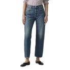 Person wearing a striped shirt and blue jeans on a plain background
