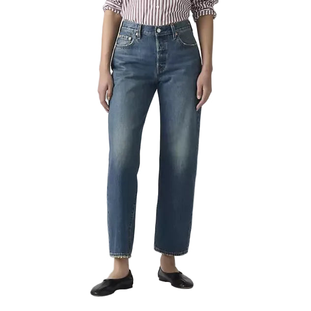 Person wearing a striped shirt and blue jeans on a plain background