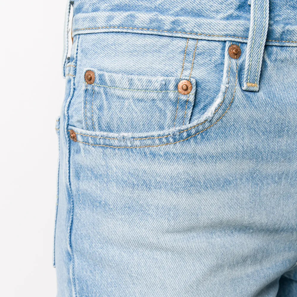 Close-up of light blue denim shorts with frayed hem on a white background