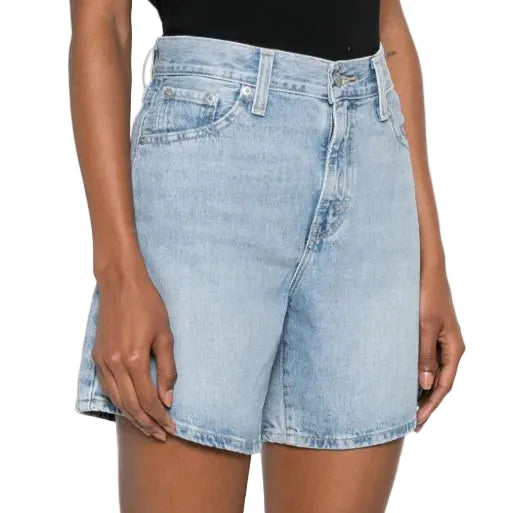 Person wearing light blue denim shorts on a white background