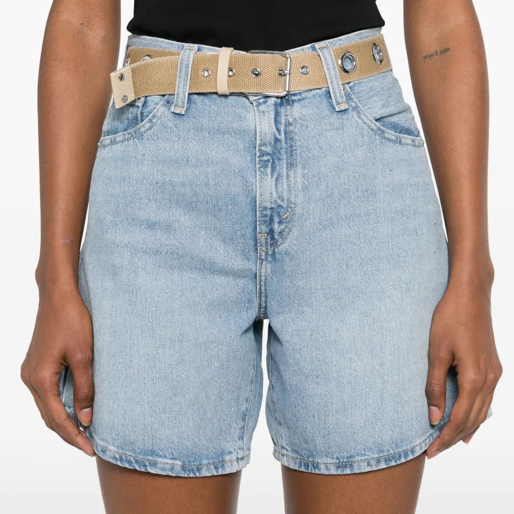 Person wearing light blue denim shorts with a beige belt on a white background