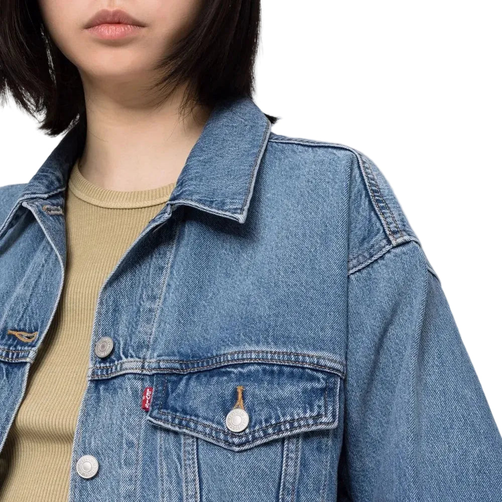 Person wearing a blue denim jacket on a plain background