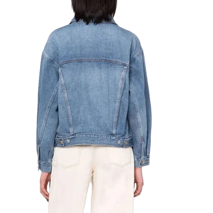 Person wearing a blue denim jacket and white pants on a plain background