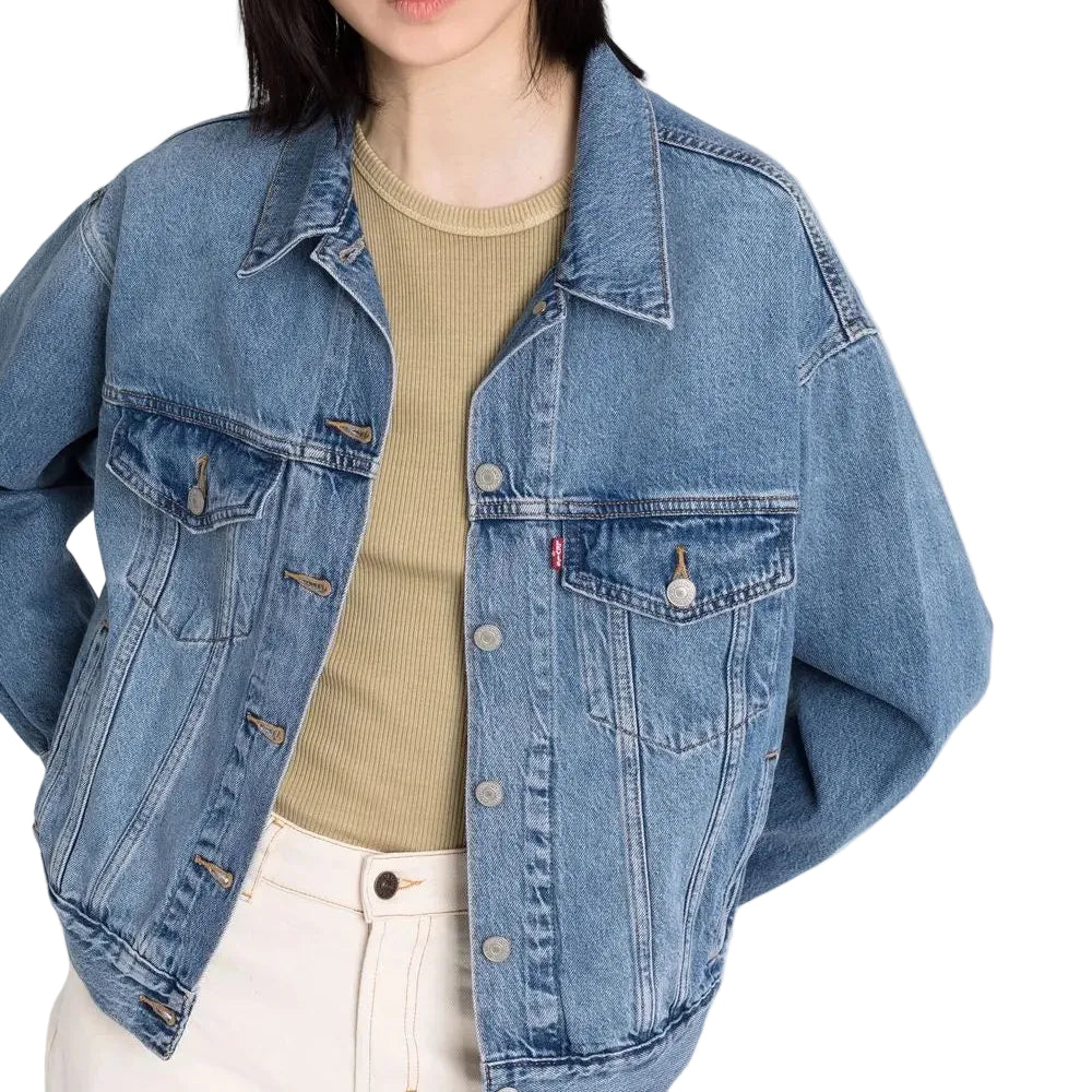 Person wearing a blue denim jacket over a beige shirt on a plain background