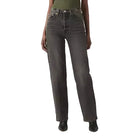 Woman wearing a green top and dark jeans on a white background