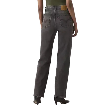 Woman wearing a green top and gray jeans on a white background