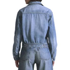 Person wearing a denim jumpsuit on a light gray background