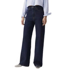 Person wearing dark blue jeans and a light blue shirt on a plain background