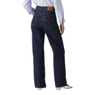 Person wearing dark blue jeans and a light blue shirt on a plain background