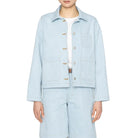 Person wearing a light blue denim jacket and pants on a white background